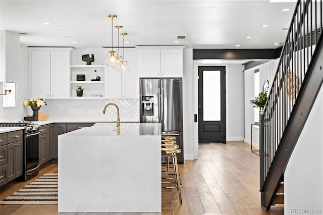 kitchen with visible vents, a sink, white cabinets, stainless steel appliances, and open shelves