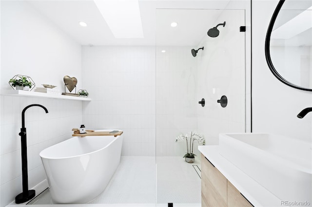 bathroom featuring a walk in shower, recessed lighting, a freestanding tub, tile walls, and a sink