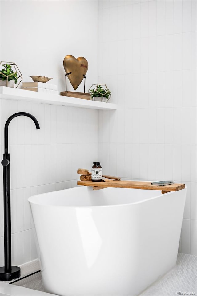 bathroom featuring tile walls and a freestanding tub