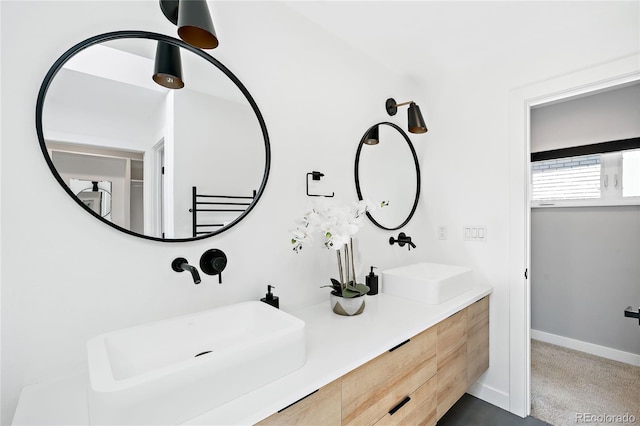 full bath with double vanity, baseboards, and a sink