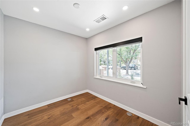 empty room featuring dark wood-type flooring, recessed lighting, baseboards, and visible vents