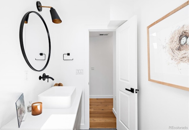 bathroom with visible vents, wood finished floors, and a sink