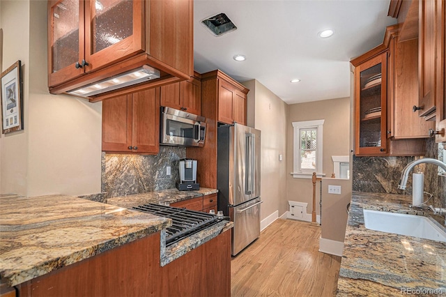 726 S Corona St, Denver, CO 80209 - kitchen with appliances with stainless steel finishes, a sink, brown cabinets, light stone counters, and recessed lighting