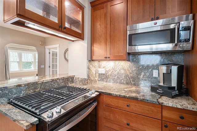 726 S Corona St, Denver, CO 80209 - kitchen featuring stainless steel microwave, gas stove, brown cabinets, and decorative backsplash