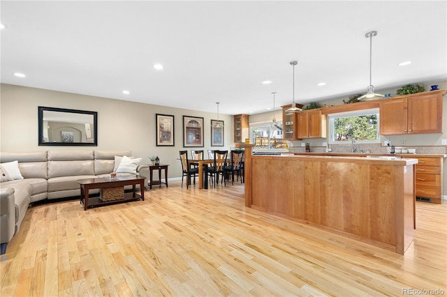 kitchen featuring light wood-type flooring, pendant lighting, a sink, open floor plan, and recessed lighting