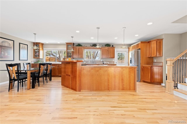 kitchen with a healthy amount of sunlight, a kitchen island, light wood finished floors, and high end refrigerator