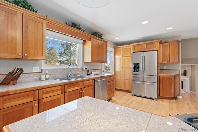 kitchen with light countertops, recessed lighting, light wood-style flooring, stainless steel appliances, and a sink