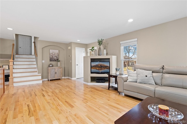 living room featuring recessed lighting, baseboards, light wood-style floors, and stairs