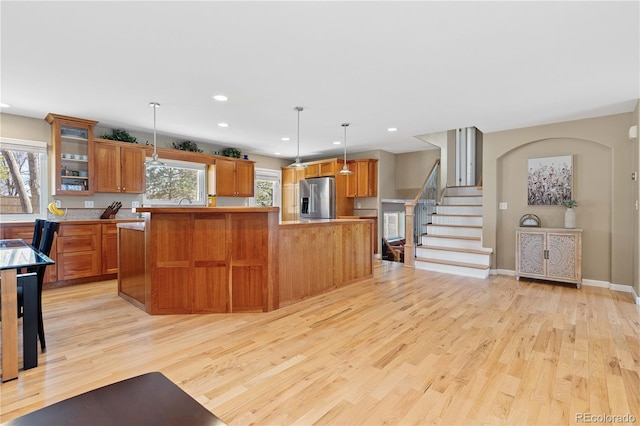 kitchen with light wood-style flooring, recessed lighting, stainless steel fridge with ice dispenser, and brown cabinets