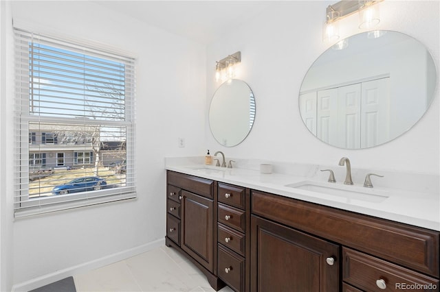 bathroom featuring a sink, baseboards, and double vanity