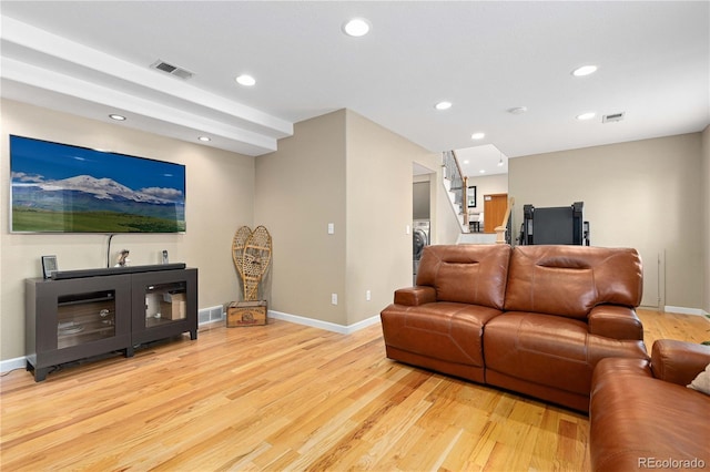 living area featuring stairs, light wood-style flooring, and visible vents