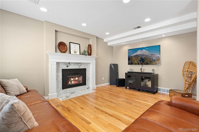 living area with visible vents, recessed lighting, wood finished floors, and a premium fireplace