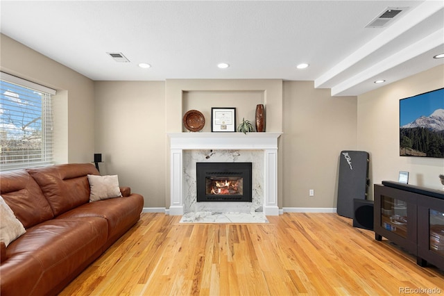 living room with wood finished floors, a fireplace, visible vents, and baseboards