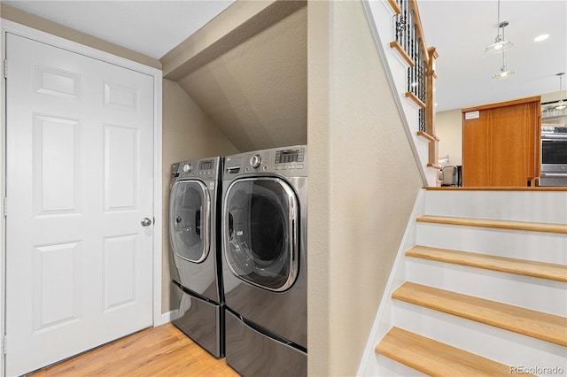 clothes washing area with laundry area, wood finished floors, independent washer and dryer, and baseboards