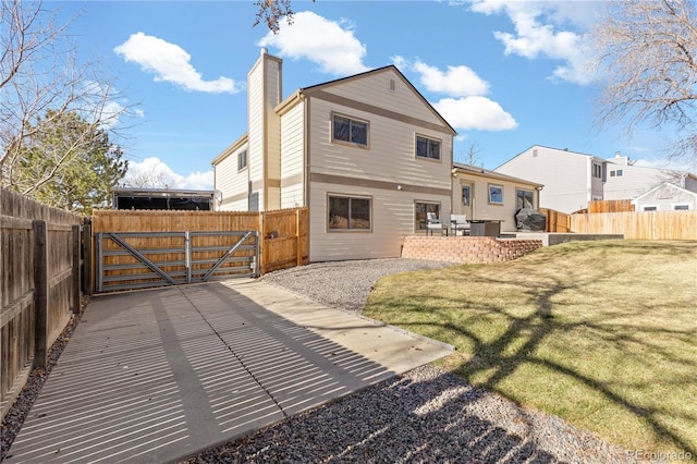 rear view of property with a gate, a patio area, a fenced backyard, and a chimney