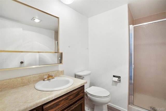 bathroom featuring vanity, toilet, and a shower with shower door