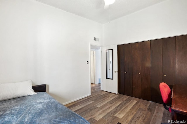 bedroom featuring a towering ceiling, dark hardwood / wood-style flooring, a closet, and ceiling fan