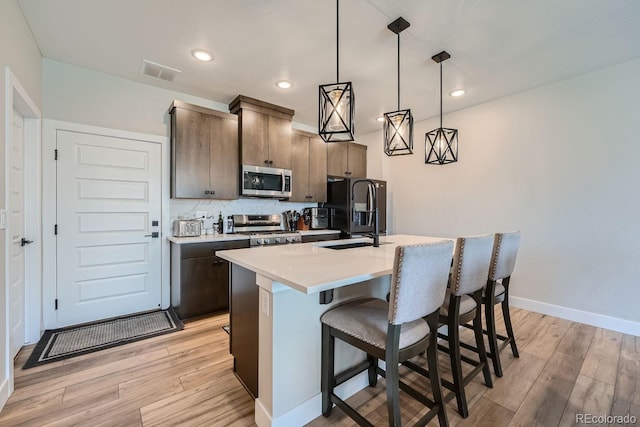 16433 Askins Loop, Parker, CO 80134 - kitchen with appliances with stainless steel finishes, a sink, a kitchen bar, light wood-type flooring, and recessed lighting