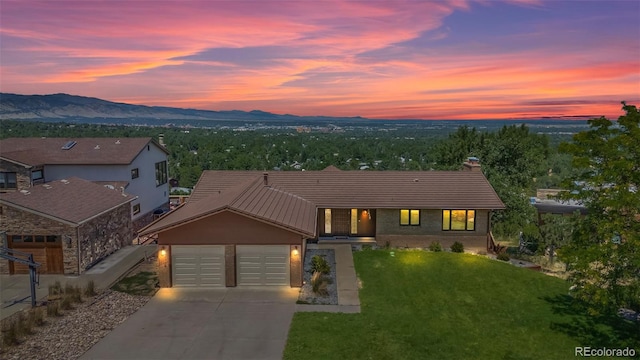 view of front of house featuring a garage, a mountain view, and a lawn