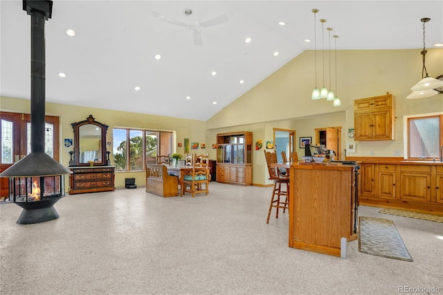 kitchen with a center island, a wood stove, high vaulted ceiling, open floor plan, and a breakfast bar