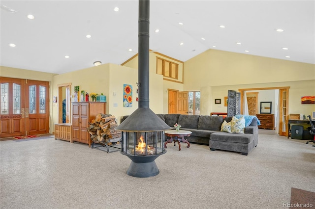carpeted living room with recessed lighting, high vaulted ceiling, and a wood stove