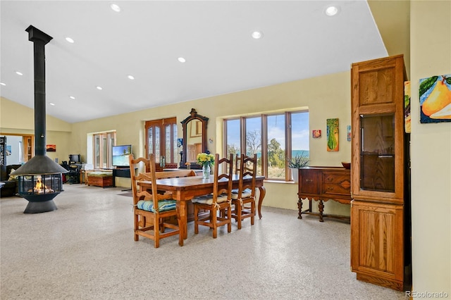 dining space featuring light speckled floor, a wood stove, recessed lighting, and lofted ceiling