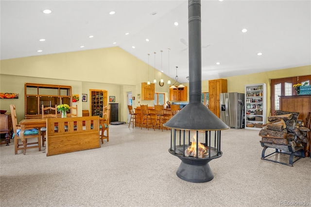 living area featuring high vaulted ceiling, a wood stove, recessed lighting, and light colored carpet