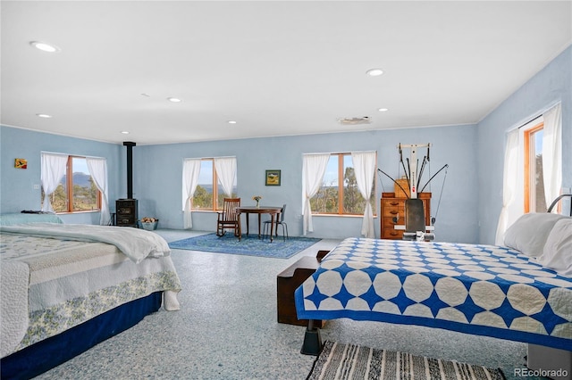 bedroom with multiple windows, a wood stove, and recessed lighting