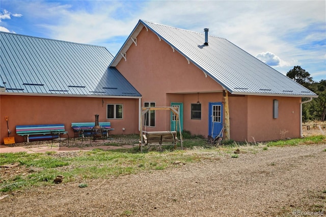 rear view of property featuring a standing seam roof, stucco siding, and metal roof