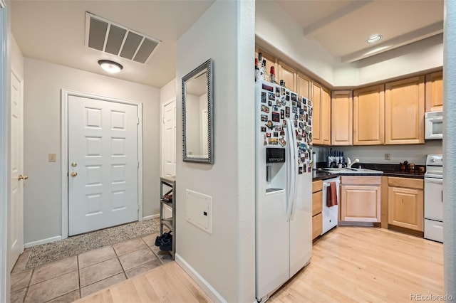 kitchen featuring light brown cabinets, light tile patterned flooring, white appliances, and sink