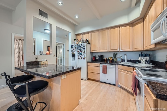 kitchen with kitchen peninsula, a breakfast bar, white appliances, sink, and light hardwood / wood-style flooring