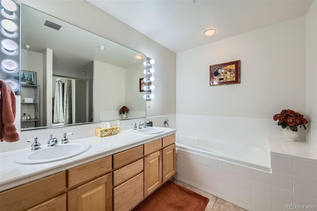 bathroom featuring tile patterned flooring, vanity, and tiled tub