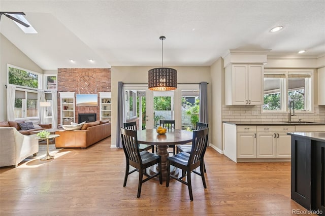 5528 S Jasper Way, Centennial, CO 80015 - dining area featuring light wood-style floors, a skylight, plenty of natural light, a brick fireplace, and lofted ceiling
