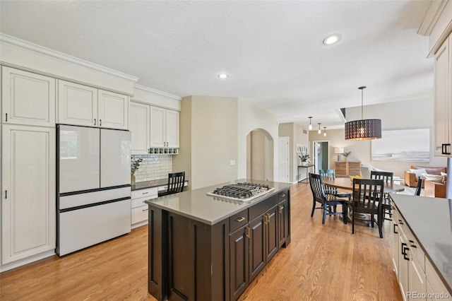 5528 S Jasper Way, Centennial, CO 80015 - kitchen with freestanding refrigerator, arched walkways, light wood finished floors, stainless steel gas stovetop, and decorative backsplash