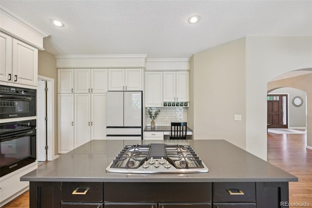 5528 S Jasper Way, Centennial, CO 80015 - kitchen featuring stainless steel gas cooktop, white refrigerator, arched walkways, decorative backsplash, and white cabinets