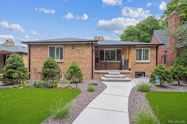 2664 Forest St, Denver, CO 80207 - view of front of house featuring brick siding, a front lawn, and a chimney
