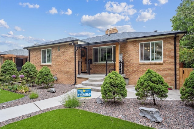 2664 Forest St, Denver, CO 80207 - view of front of property with brick siding, a chimney, covered porch, and roof with shingles