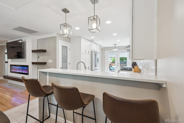 2664 Forest St, Denver, CO 80207 - kitchen with high quality fridge, light countertops, a kitchen bar, white cabinetry, and decorative light fixtures