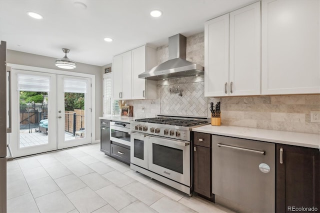 2664 Forest St, Denver, CO 80207 - kitchen with wall chimney range hood, range with two ovens, light countertops, white cabinets, and french doors