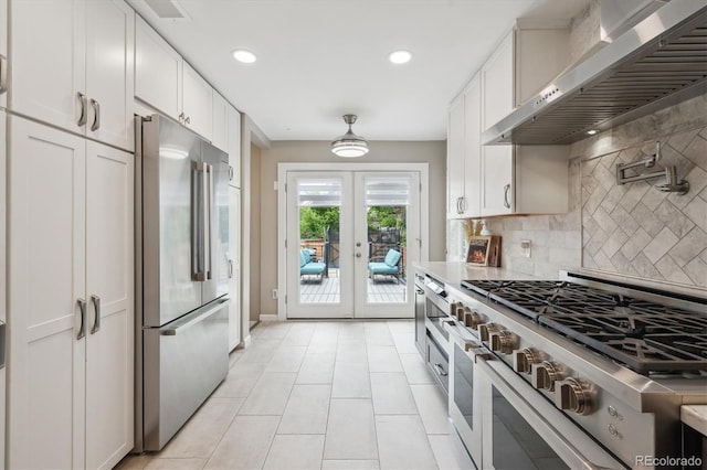 2664 Forest St, Denver, CO 80207 - kitchen featuring high end appliances, extractor fan, light tile patterned floors, tasteful backsplash, and white cabinetry