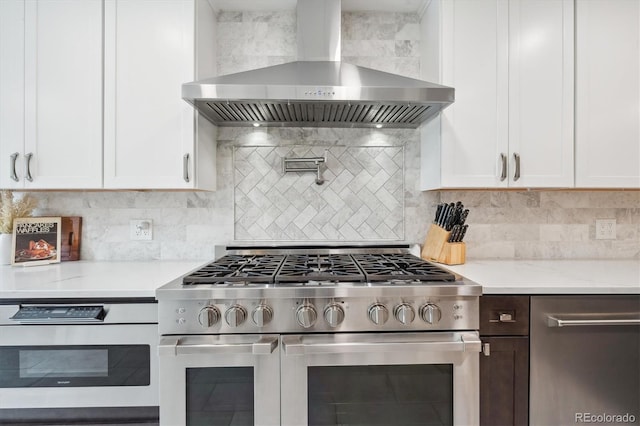 2664 Forest St, Denver, CO 80207 - kitchen with high end range, wall chimney range hood, white cabinets, and decorative backsplash