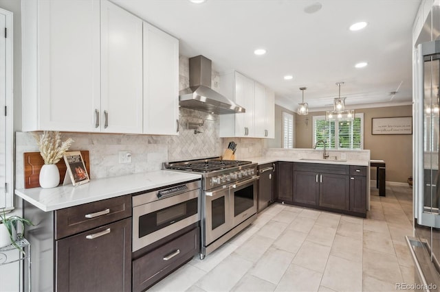 2664 Forest St, Denver, CO 80207 - kitchen featuring wall chimney range hood, stainless steel appliances, a sink, dark brown cabinetry, and recessed lighting