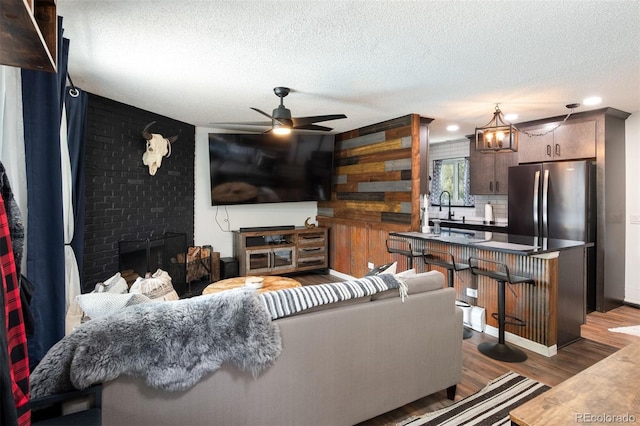 2700 S Holly St Unit 202, Denver, CO 80222 - living room with a textured ceiling, ceiling fan, wood finished floors, a brick fireplace, and recessed lighting