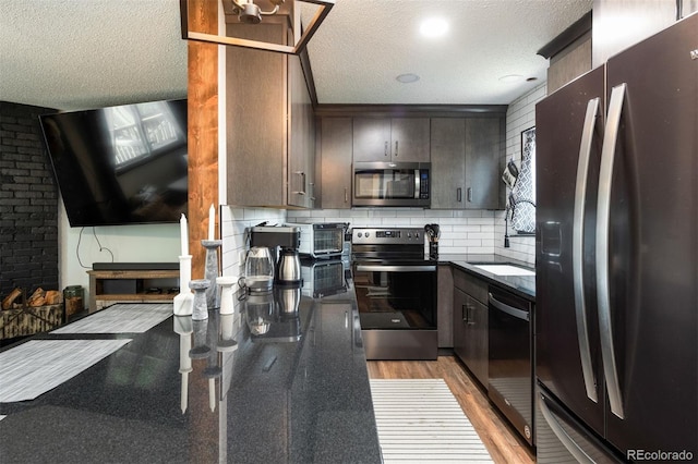 2700 S Holly St Unit 202, Denver, CO 80222 - kitchen featuring appliances with stainless steel finishes, a textured ceiling, dark countertops, decorative backsplash, and light wood finished floors