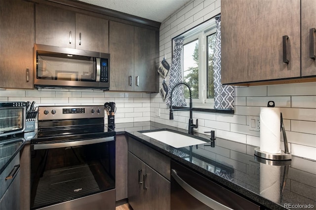 2700 S Holly St Unit 202, Denver, CO 80222 - kitchen with appliances with stainless steel finishes, dark brown cabinetry, tasteful backsplash, a textured ceiling, and dark stone countertops