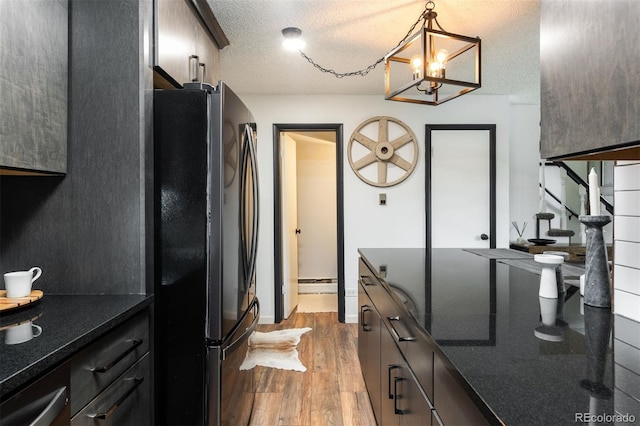 2700 S Holly St Unit 202, Denver, CO 80222 - kitchen featuring freestanding refrigerator, wood finished floors, a textured ceiling, baseboard heating, and a chandelier