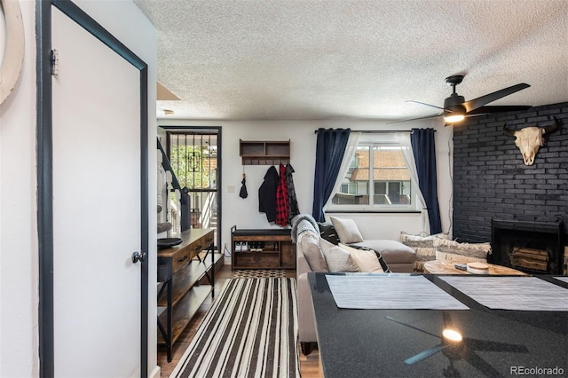 2700 S Holly St Unit 202, Denver, CO 80222 - living room featuring a ceiling fan, a fireplace, a textured ceiling, healthy amount of natural light, and wood finished floors