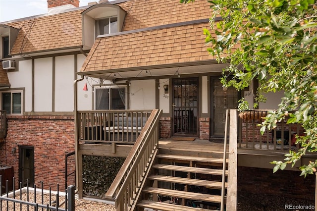 2700 S Holly St Unit 202, Denver, CO 80222 - entrance to property featuring a shingled roof, stucco siding, mansard roof, a chimney, and covered porch