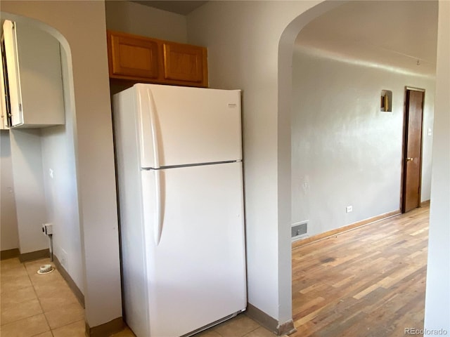 3820-3830 Pierce St, Wheat Ridge, CO 80033 - kitchen featuring freestanding refrigerator, arched walkways, brown cabinets, and light wood finished floors