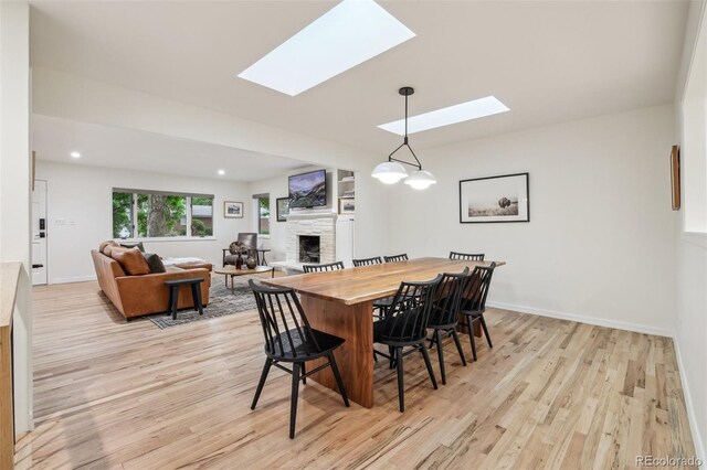 632 Wyoming St, Golden, CO 80403 - dining area featuring a fireplace, a skylight, light wood-type flooring, and baseboards